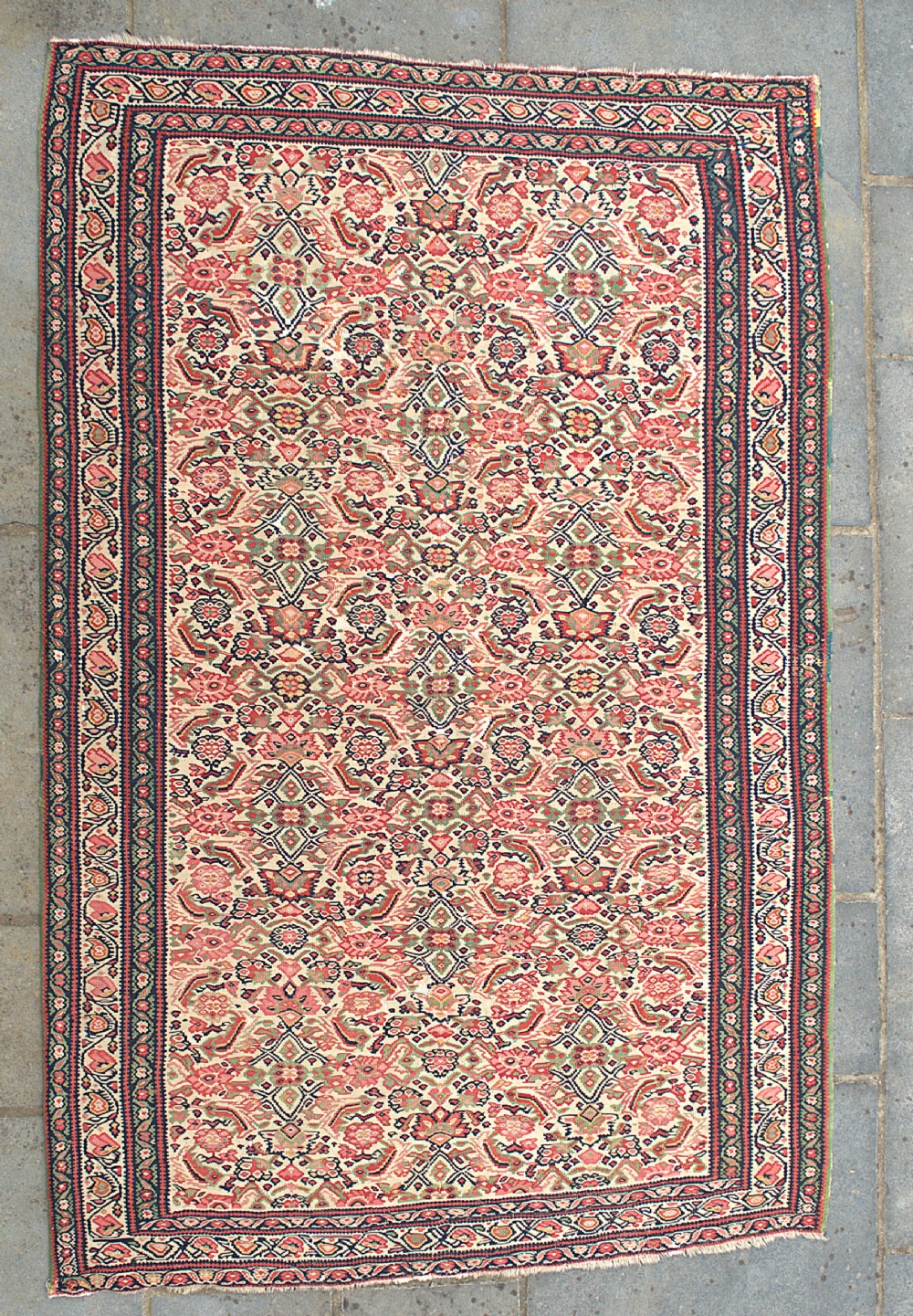 An antique flat-weave Senneh kilim featuring a dense repeating floral and geometric field in shades of terracotta red, cream, navy blue, and green with framed multi-bordered edges.