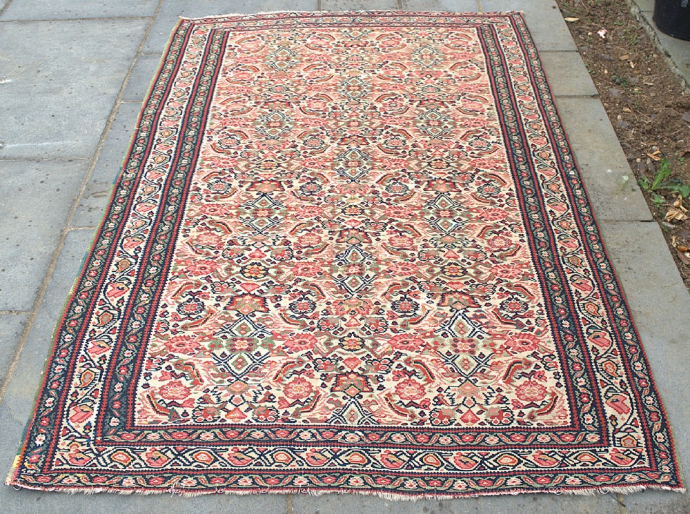 An antique flat-weave Senneh kilim featuring a dense repeating floral and geometric field in shades of terracotta red, cream, navy blue, and green with framed multi-bordered edges. View II