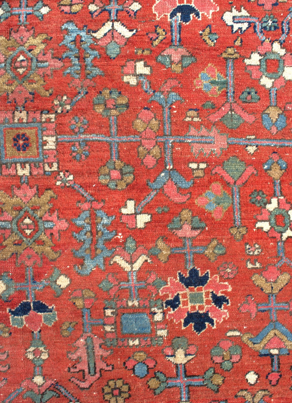A large antique Persian Heriz wool carpet featuring a terracotta red field with geometric floral motifs and a dark navy blue outer border. View II