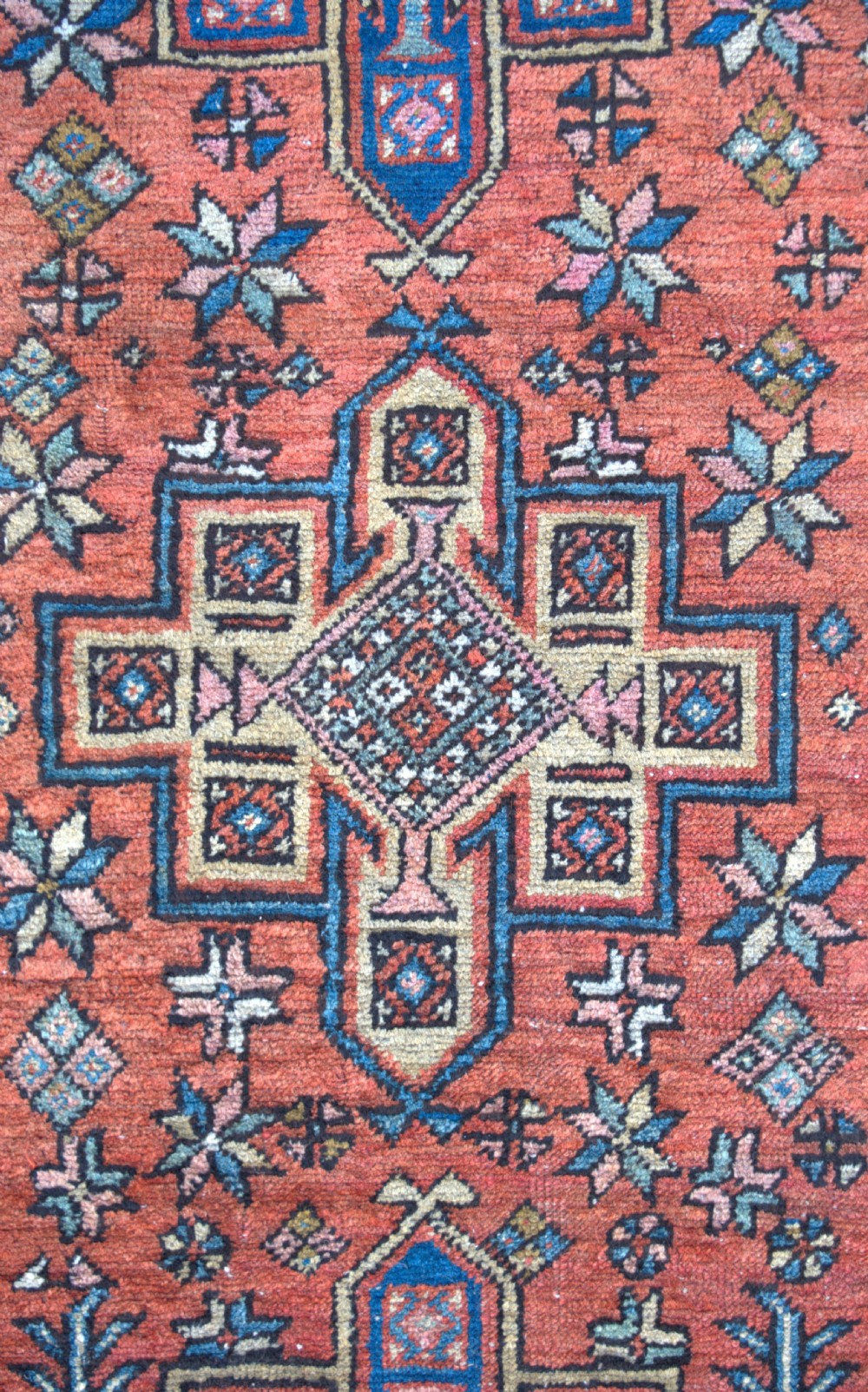 An antique Persian Heriz wool runner rug featuring repeating geometric medallions on a terracotta red field with blue and cream borders. View VIII