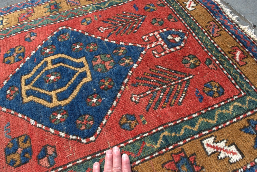 An antique hand-knotted Persian Heriz runner rug featuring five blue diamond medallions along a red field with ochre borders. View IV