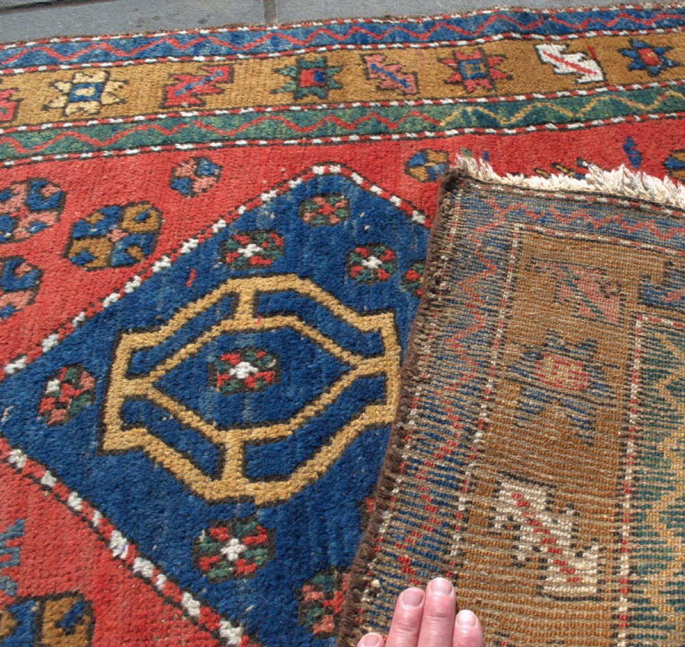 An antique hand-knotted Persian Heriz runner rug featuring five blue diamond medallions along a red field with ochre borders. View V