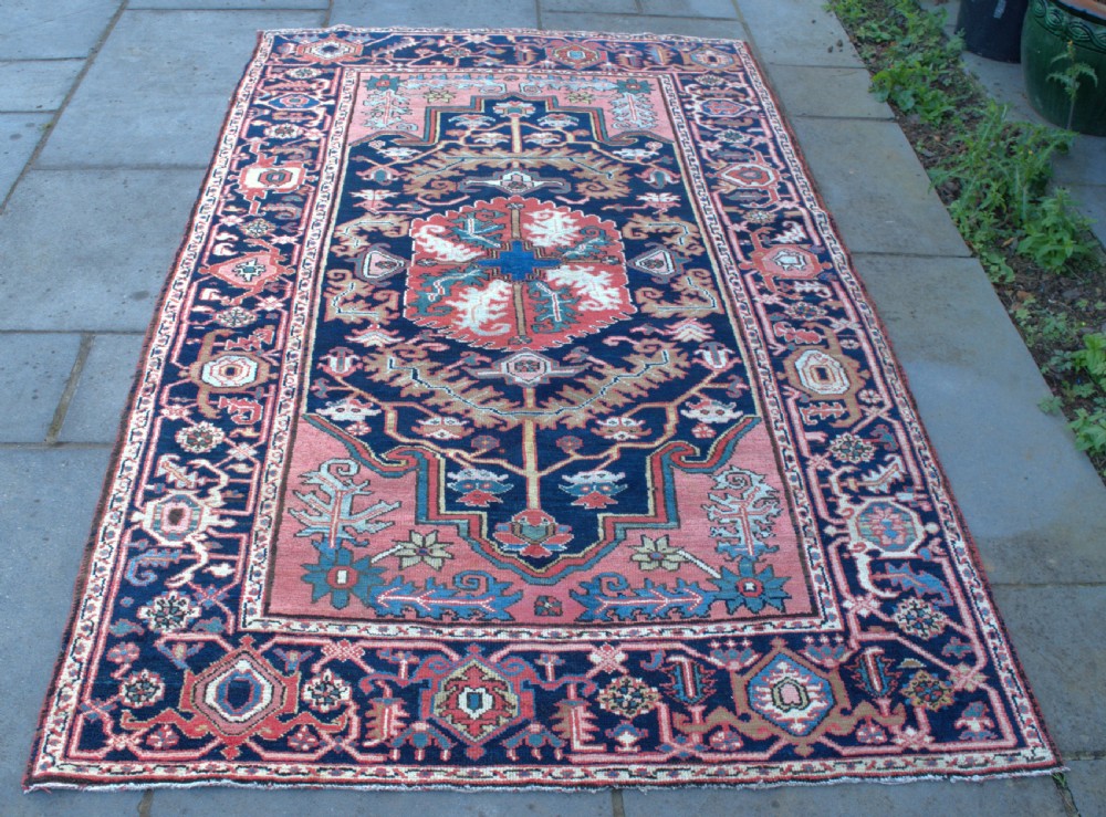 An antique hand-knotted Persian Heriz wool rug featuring a geometric central medallion in terracotta and blue on a navy field framed by a detailed border. View II