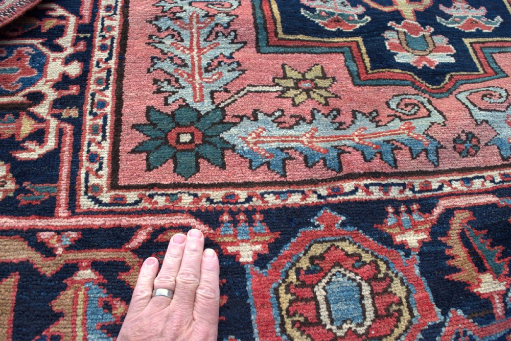 An antique hand-knotted Persian Heriz wool rug featuring a geometric central medallion in terracotta and blue on a navy field framed by a detailed border. View IV