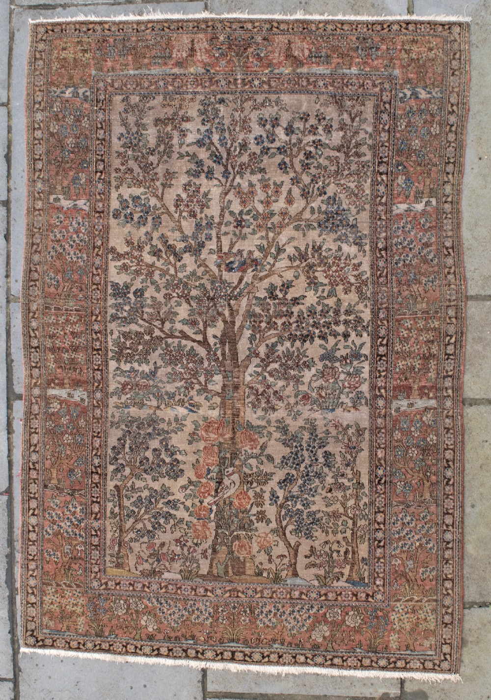 An antique Persian Isfahan wool rug featuring a central Tree of Life pictorial motif with birds framed by a terracotta floral border.