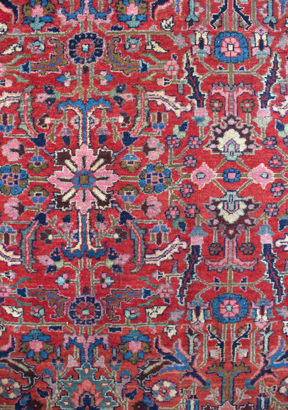 A large hand-knotted wool Heriz carpet featuring an intricate red central field decorated with geometric floral motifs and a dark navy border. View II