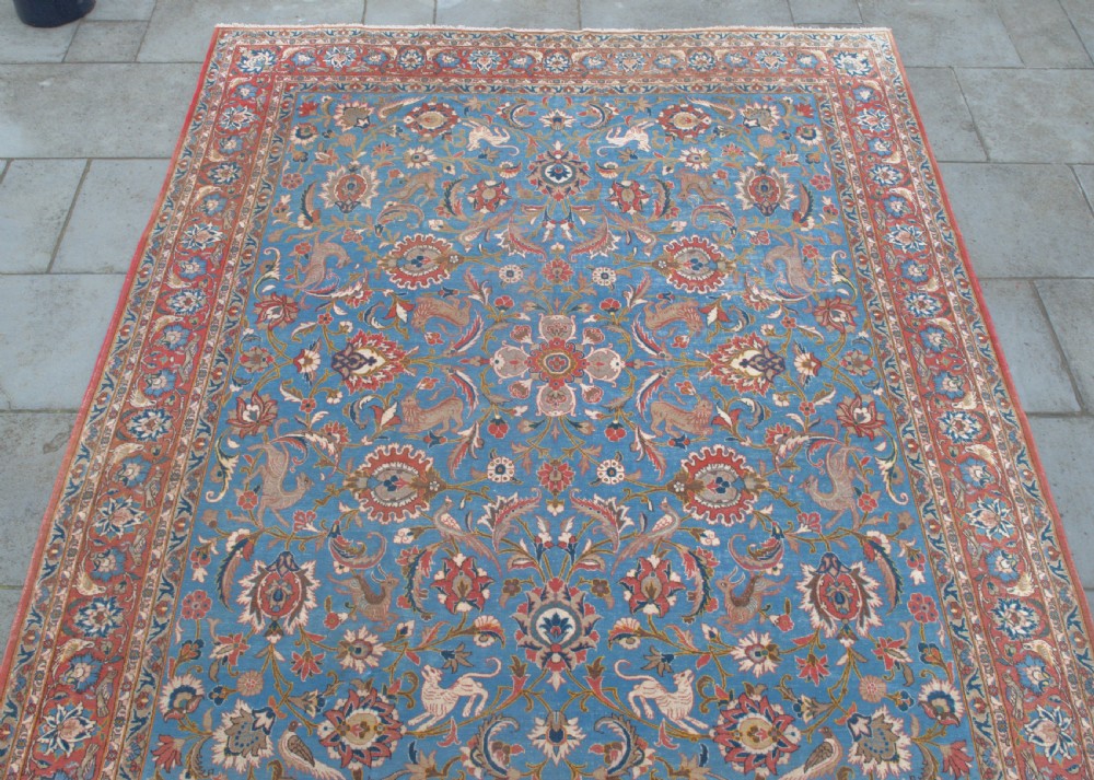 A large hand-knotted wool Veramin carpet featuring a central sky-blue field detailed with animals, birds, and floral vine scrolls inside a red multi-bordered frame. View III