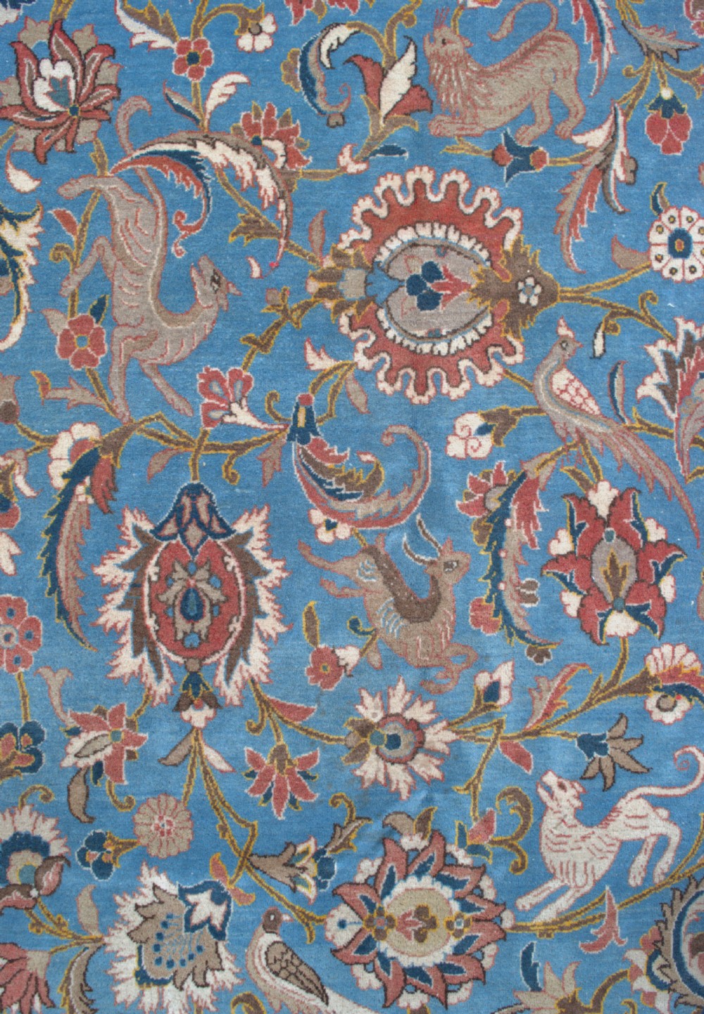 A large hand-knotted wool Veramin carpet featuring a central sky-blue field detailed with animals, birds, and floral vine scrolls inside a red multi-bordered frame. View V