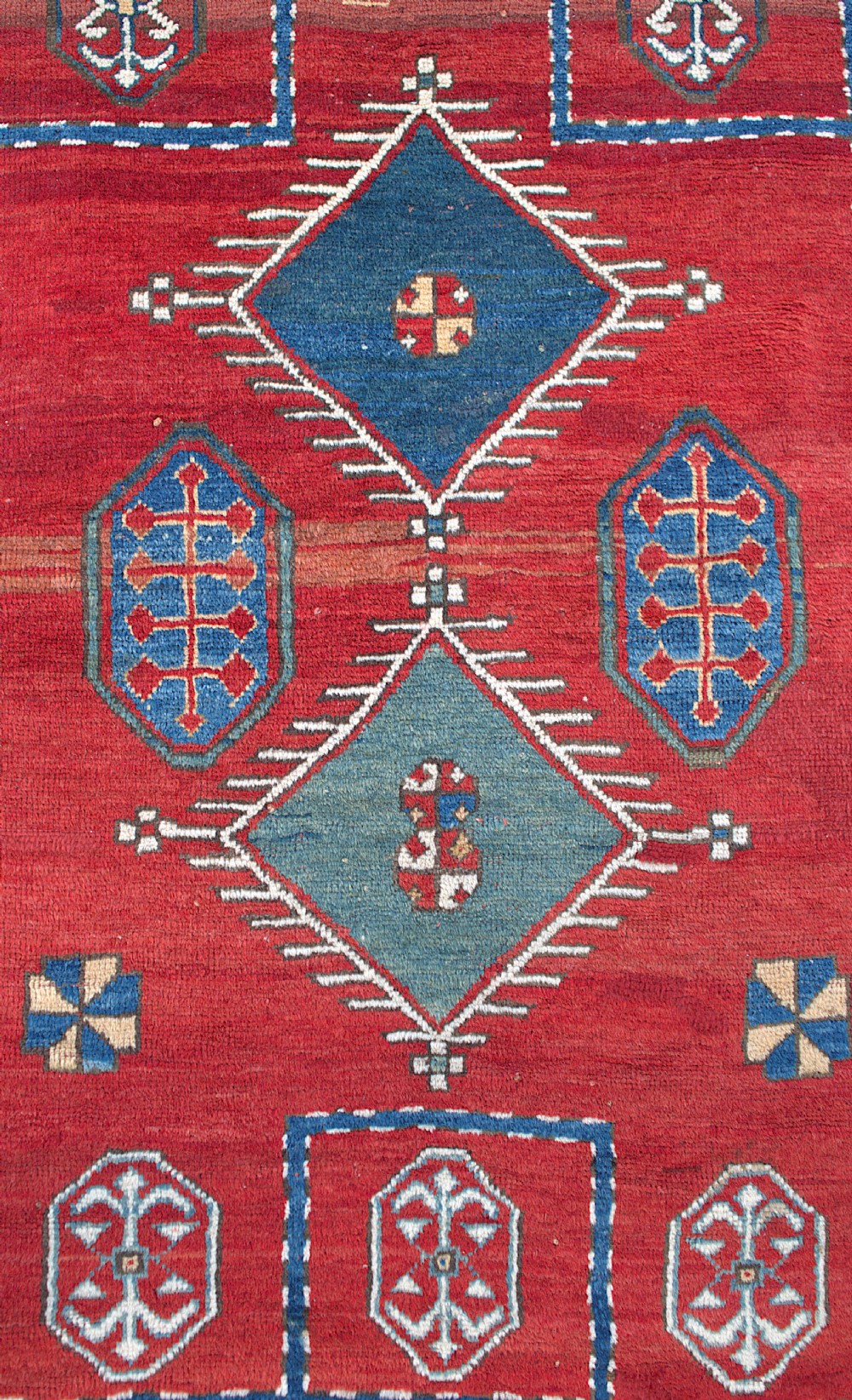 An antique Caucasian Kazak hand-knotted wool prayer rug featuring geometric diamond medallions on a red field framed by multiple patterned borders. View IV