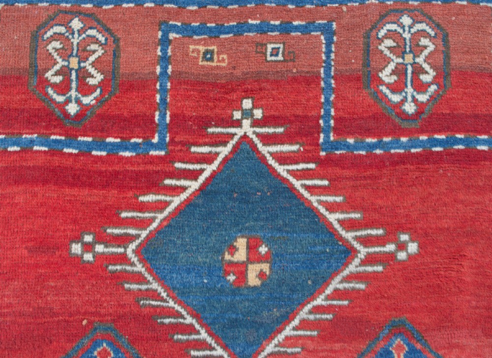 An antique Caucasian Kazak hand-knotted wool prayer rug featuring geometric diamond medallions on a red field framed by multiple patterned borders. View VIII