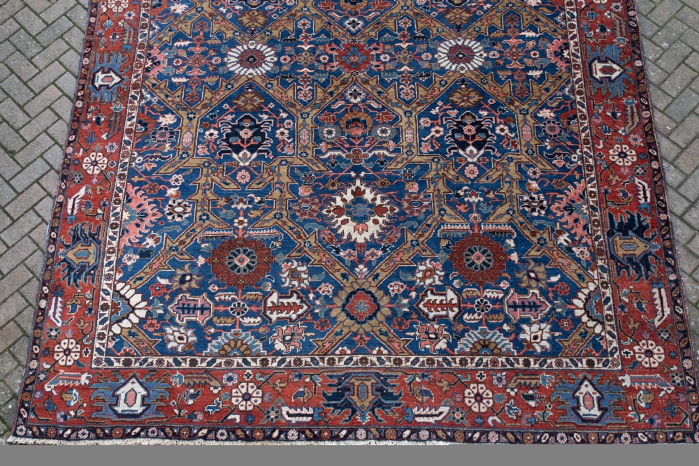 A large hand-knotted antique Heriz wool carpet featuring geometric floral motifs in deep blue, terracotta red, and ivory tones. View II