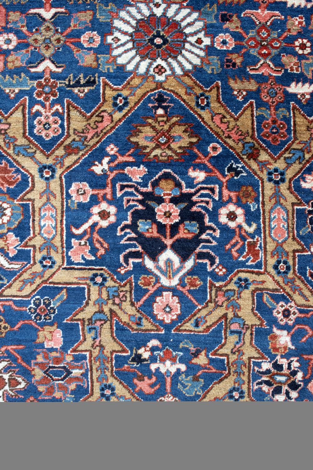 A large hand-knotted antique Heriz wool carpet featuring geometric floral motifs in deep blue, terracotta red, and ivory tones. View V