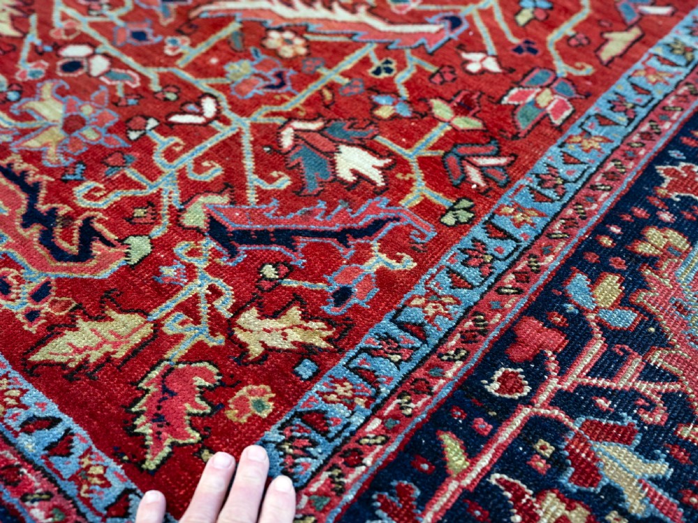 A rectangular hand-knotted Persian Heriz carpet featuring an intricate all-over geometric floral design in terracotta red, light blue, and navy blue tones. View III