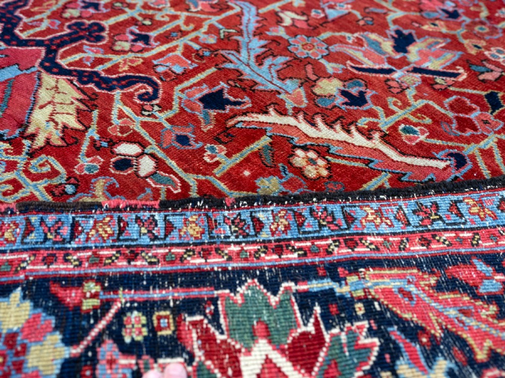A rectangular hand-knotted Persian Heriz carpet featuring an intricate all-over geometric floral design in terracotta red, light blue, and navy blue tones. View V