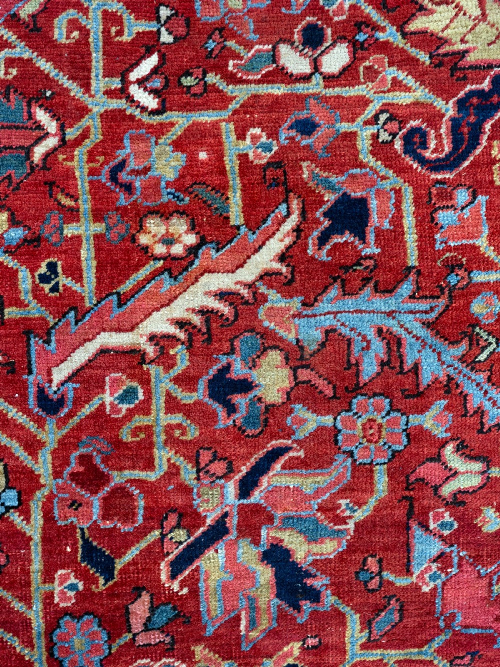 A rectangular hand-knotted Persian Heriz carpet featuring an intricate all-over geometric floral design in terracotta red, light blue, and navy blue tones. View VI