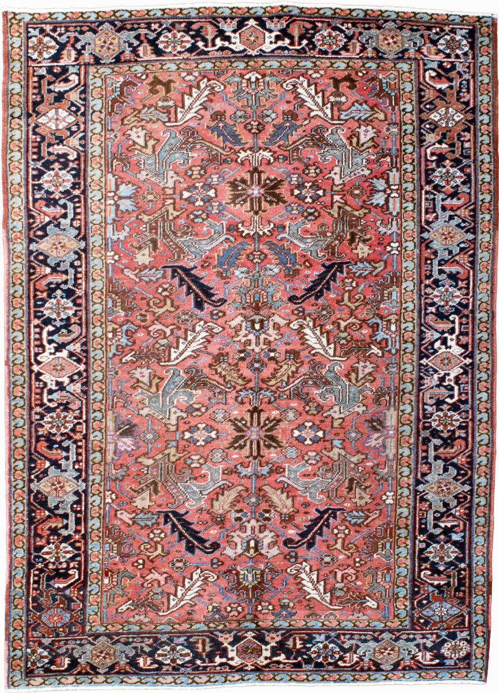 An antique Heriz wool carpet featuring a rust red field with geometric floral patterns framed by a dark navy patterned border.