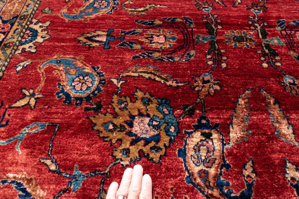 A large hand-knotted Persian Kashan carpet featuring a detailed red field covered in floral motifs framed by a multi-tiered navy blue border. View III