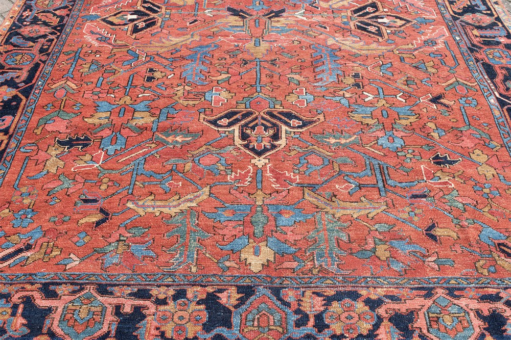 An antique Persian Heriz carpet featuring a central geometric medallion on a terracotta red field surrounded by navy blue borders. View IV