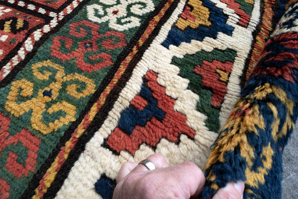 An antique Borchalu Kazak wool rug featuring stacked central diamond medallions surrounded by geometric borders in red, blue, green, and cream. View VI