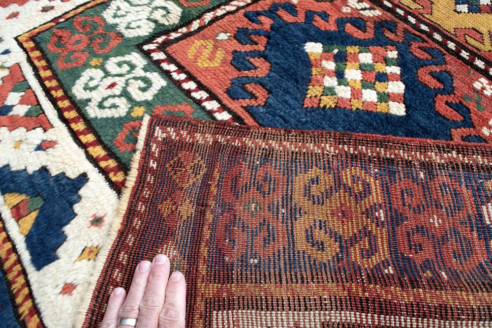 An antique Borchalu Kazak wool rug featuring stacked central diamond medallions surrounded by geometric borders in red, blue, green, and cream. View VII