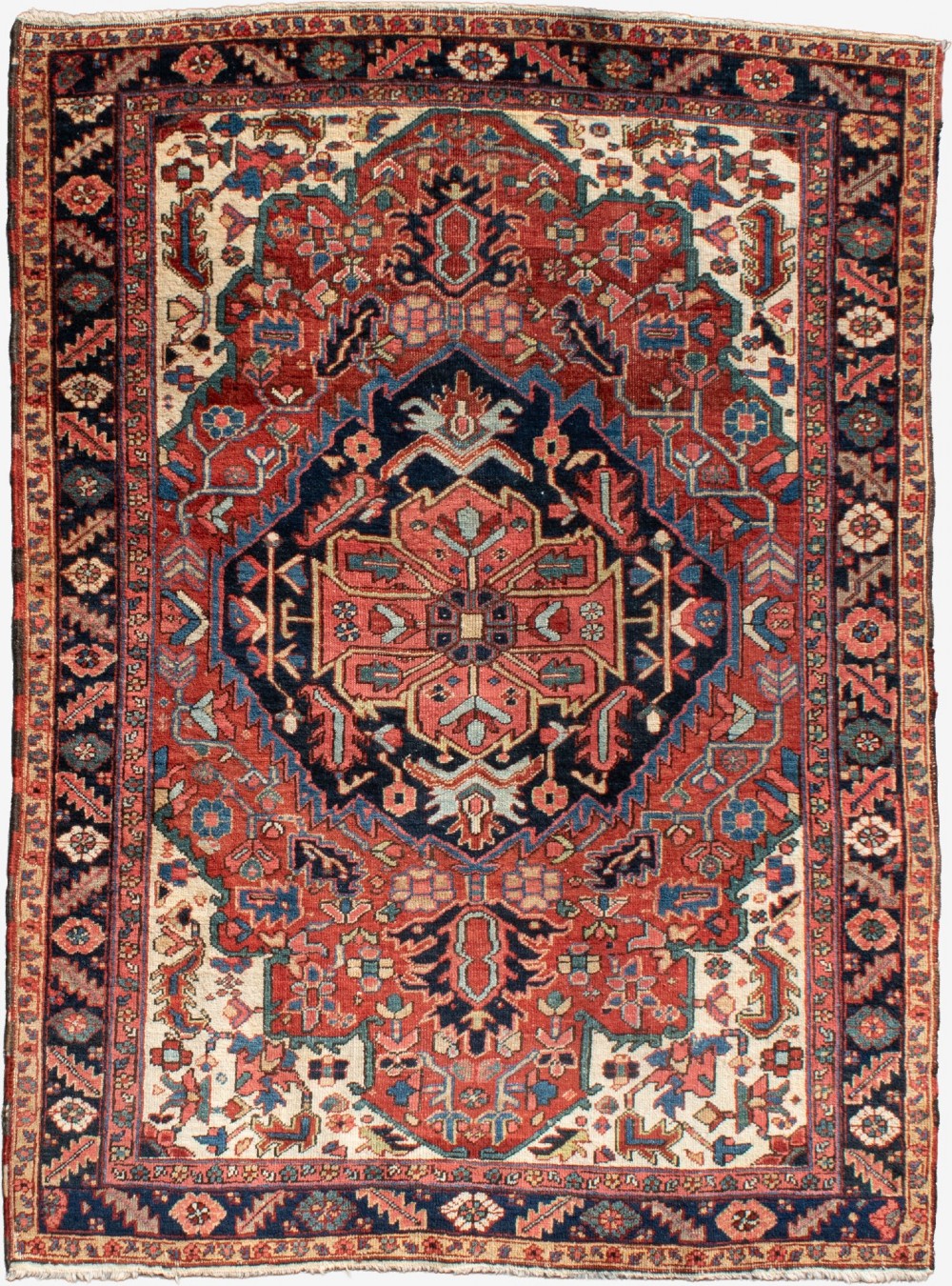 An antique Persian Heriz rug featuring a prominent central geometric medallion in navy and terracotta surrounded by patterned borders.