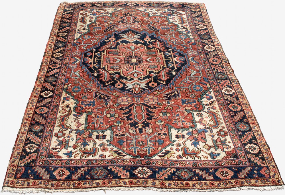 An antique Persian Heriz rug featuring a prominent central geometric medallion in navy and terracotta surrounded by patterned borders. View II