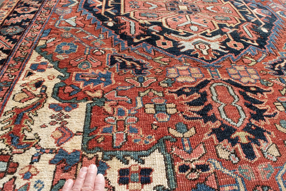 An antique Persian Heriz rug featuring a prominent central geometric medallion in navy and terracotta surrounded by patterned borders. View V