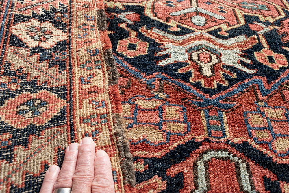 An antique Persian Heriz rug featuring a prominent central geometric medallion in navy and terracotta surrounded by patterned borders. View VI
