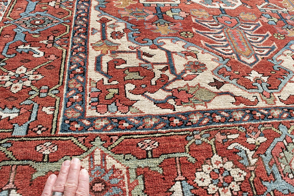 An antique Persian Serapi rug featuring a large central geometric diamond medallion in soft blue and terracotta on a red field with ivory spandrels. View VI