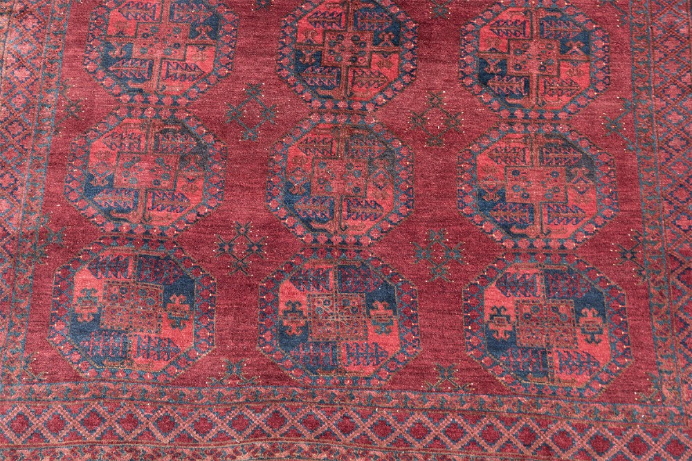 A large hand-knotted wool Afghan carpet featuring repeating octagonal gul motifs on a rich deep red field with geometric borders. View III