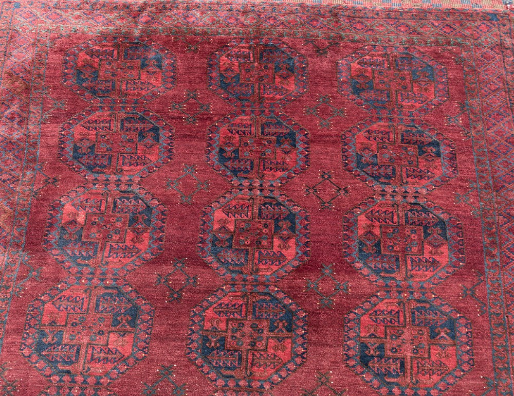 A large hand-knotted wool Afghan carpet featuring repeating octagonal gul motifs on a rich deep red field with geometric borders. View IV