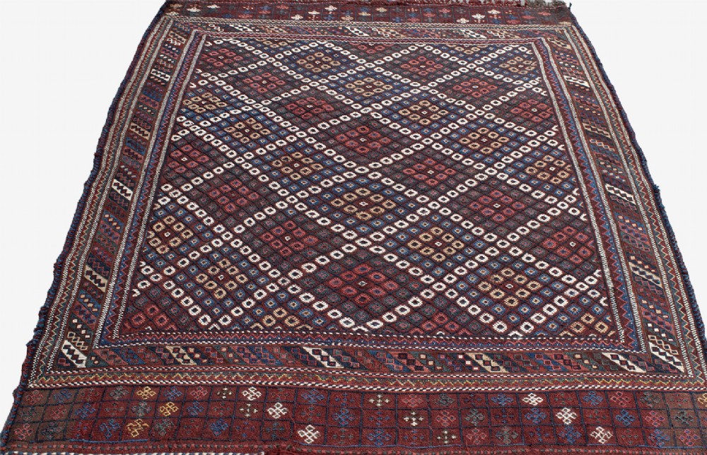 An antique Persian Afshar flatwoven Sofreh rug with a geometric diamond lattice pattern in crimson red, navy blue, and cream. View III