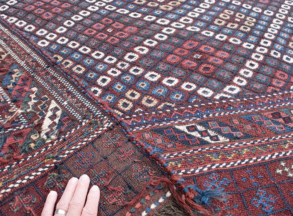 An antique Persian Afshar flatwoven Sofreh rug with a geometric diamond lattice pattern in crimson red, navy blue, and cream. View VI