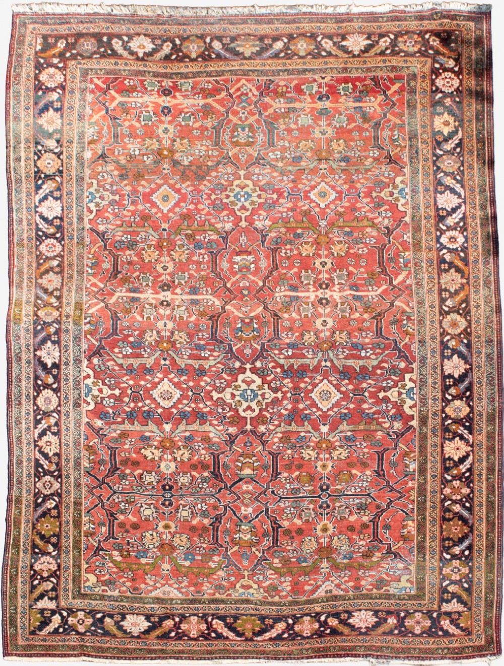 A large hand-knotted antique Persian Mahal carpet featuring a terracotta field filled with an intricate floral lattice pattern framed by a navy blue floral border.