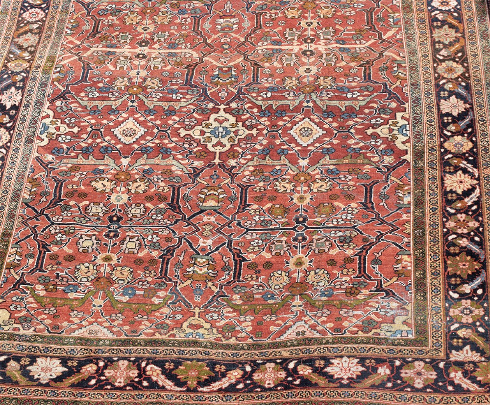 A large hand-knotted antique Persian Mahal carpet featuring a terracotta field filled with an intricate floral lattice pattern framed by a navy blue floral border. View III