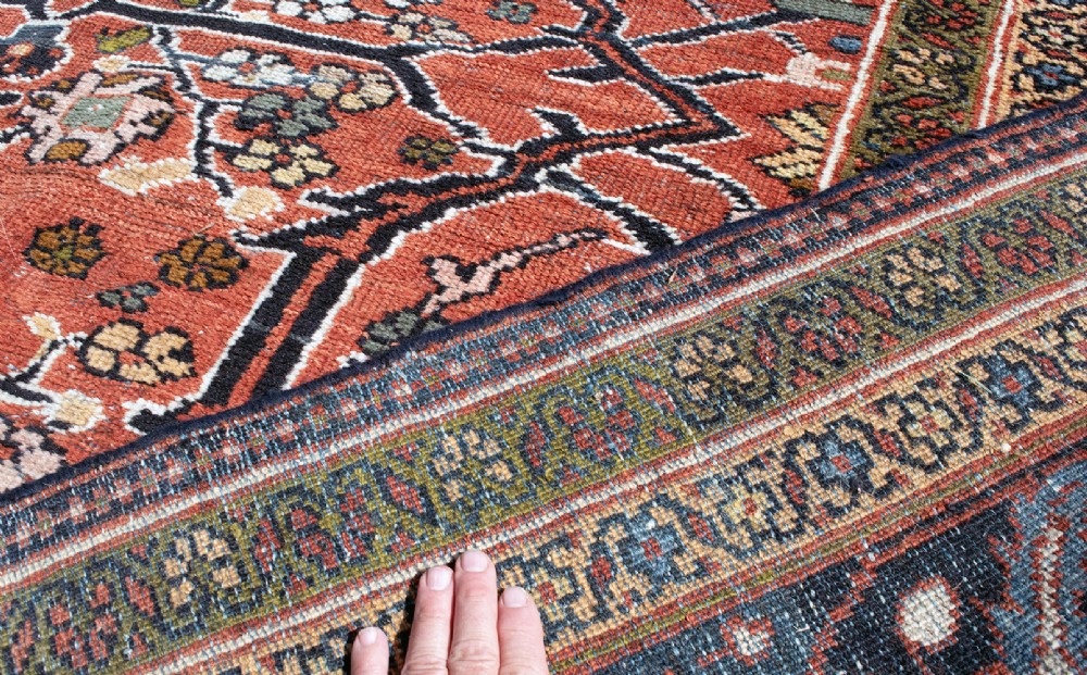 A large hand-knotted antique Persian Mahal carpet featuring a terracotta field filled with an intricate floral lattice pattern framed by a navy blue floral border. View IX