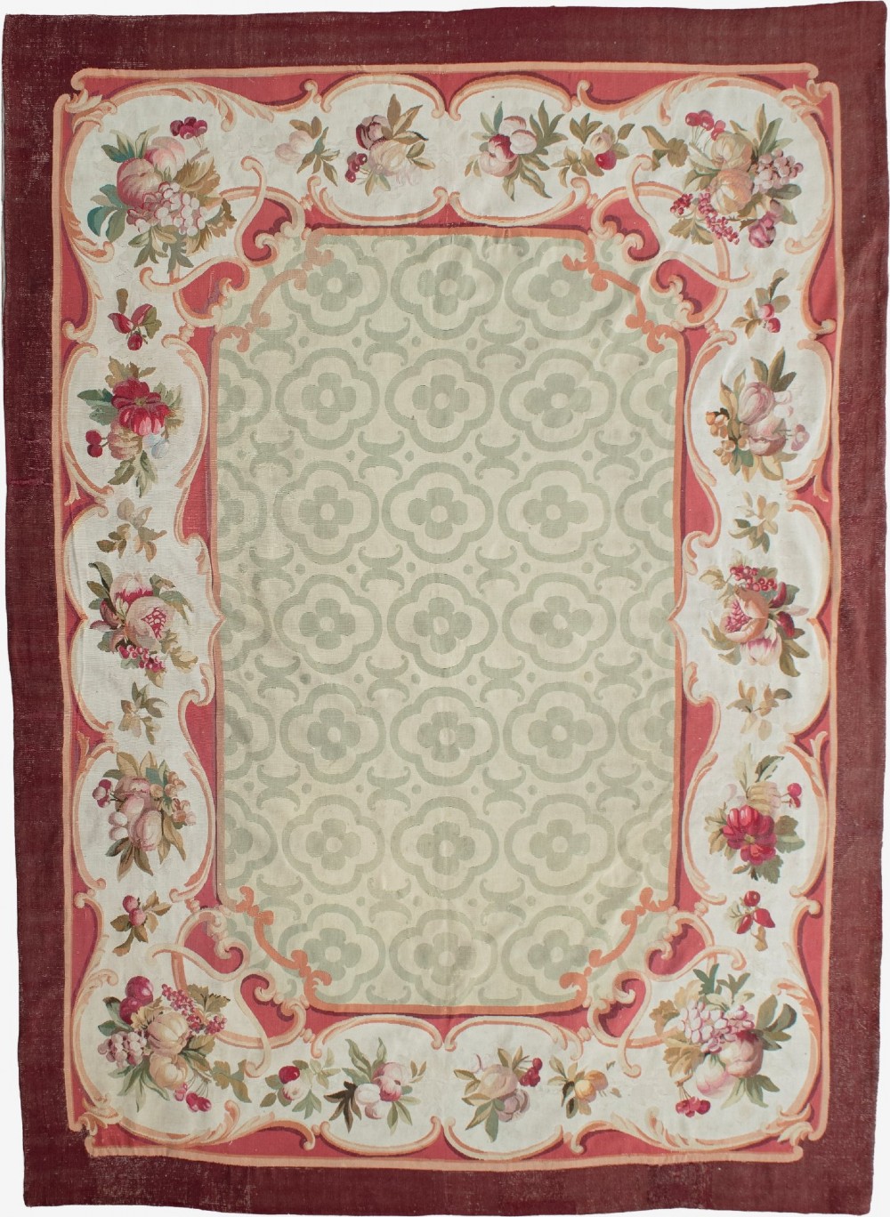 An antique French Aubusson flat-weave carpet featuring a central sage green geometric field framed by a rich floral cartouche border and a solid burgundy outer rim.