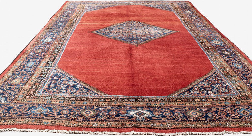 A large hand-knotted antique Ferahan wool carpet featuring a terracotta red field, a central diamond-shaped blue medallion, and detailed ornamental borders. View III