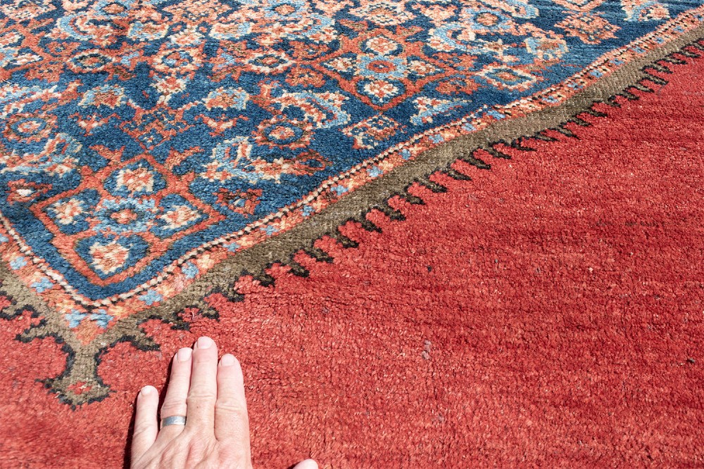 A large hand-knotted antique Ferahan wool carpet featuring a terracotta red field, a central diamond-shaped blue medallion, and detailed ornamental borders. View IV