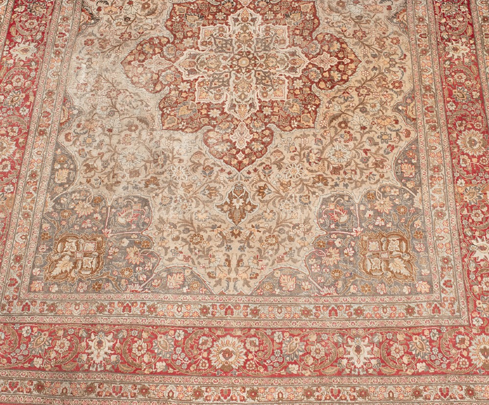 A large Persian Tabriz carpet featuring a central floral medallion on a cream field framed by deep red borders. View III