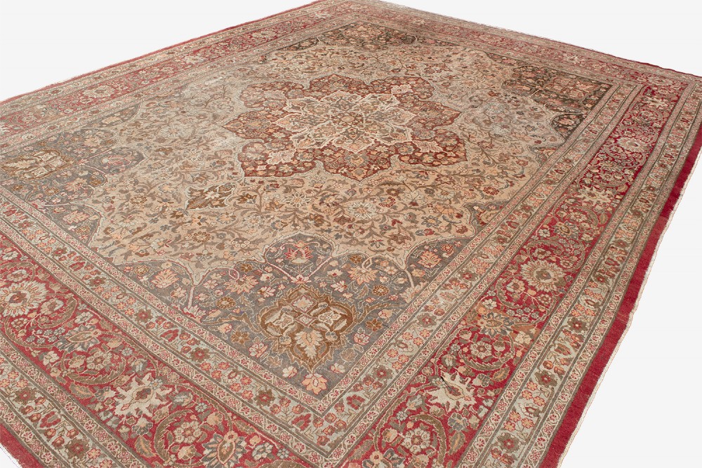 A large Persian Tabriz carpet featuring a central floral medallion on a cream field framed by deep red borders. View V