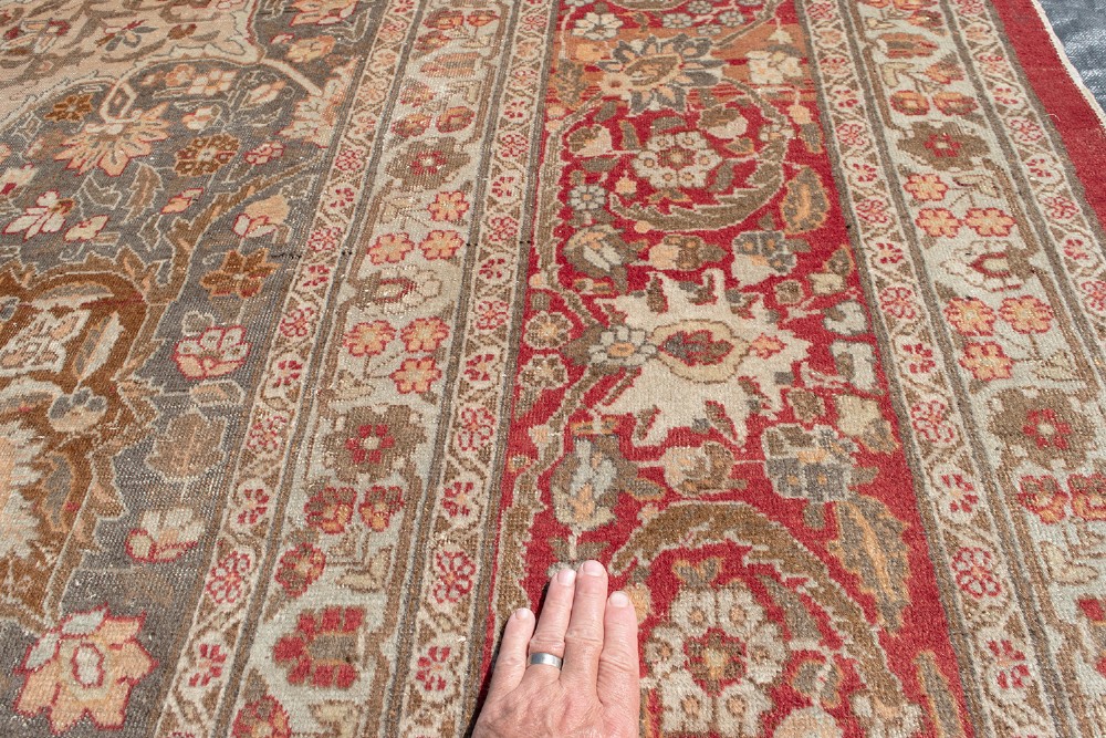 A large Persian Tabriz carpet featuring a central floral medallion on a cream field framed by deep red borders. View VI