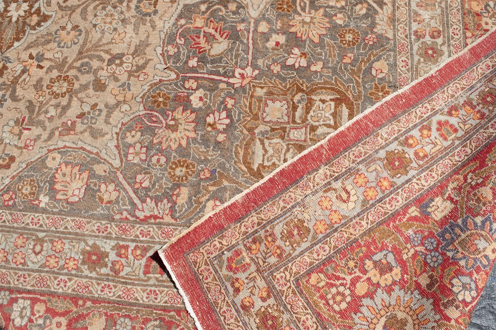 A large Persian Tabriz carpet featuring a central floral medallion on a cream field framed by deep red borders. View X