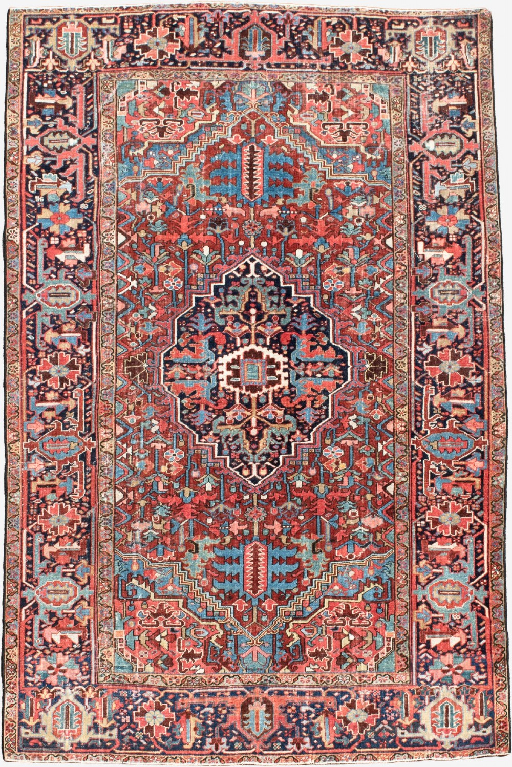 A hand-knotted Heriz wool rug featuring a central navy and ivory geometric medallion on a terracotta red field surrounded by intricate floral borders.