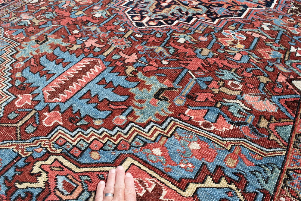 A hand-knotted Heriz wool rug featuring a central navy and ivory geometric medallion on a terracotta red field surrounded by intricate floral borders. View V