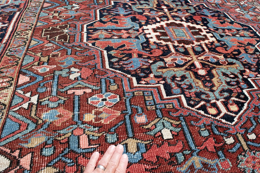 A hand-knotted Heriz wool rug featuring a central navy and ivory geometric medallion on a terracotta red field surrounded by intricate floral borders. View VII