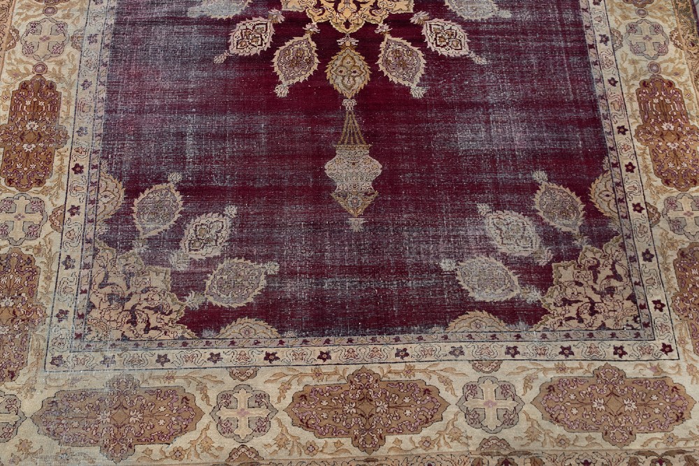 A large hand-knotted wool carpet featuring a central starburst medallion surrounded by floral motifs on a deep magenta field with a broad cream patterned border. View II