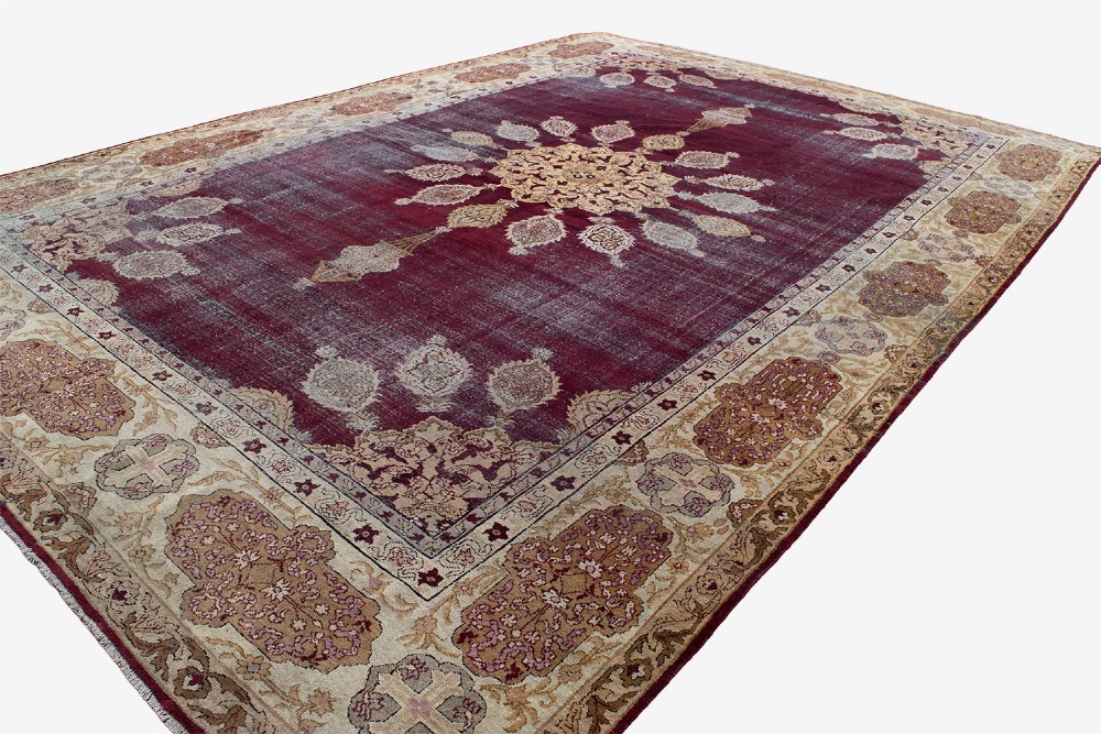 A large hand-knotted wool carpet featuring a central starburst medallion surrounded by floral motifs on a deep magenta field with a broad cream patterned border. View IV