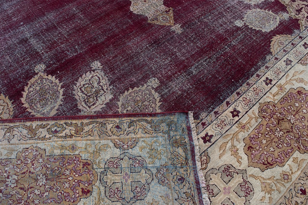 A large hand-knotted wool carpet featuring a central starburst medallion surrounded by floral motifs on a deep magenta field with a broad cream patterned border. View IX