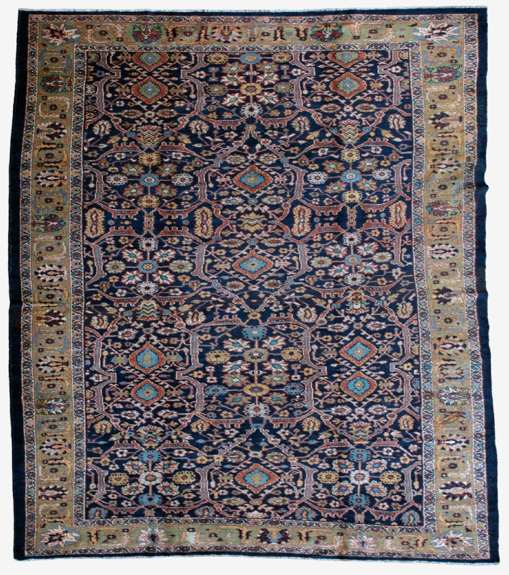 A large hand-knotted antique Persian Mahal carpet featuring intricate floral palmette patterns in navy, terracotta, and soft green across a dark blue field.